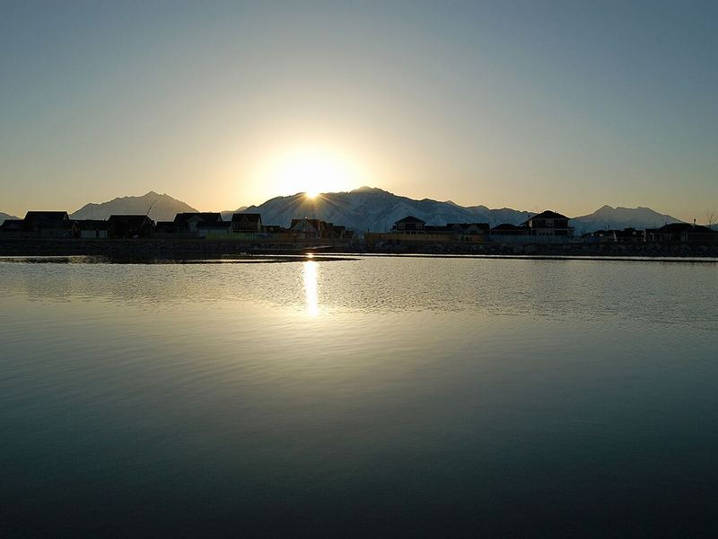 Sunrise over the Wasatch Mountains reflected in Oquirrh Lake at Daybreak in South Jordan, Utah